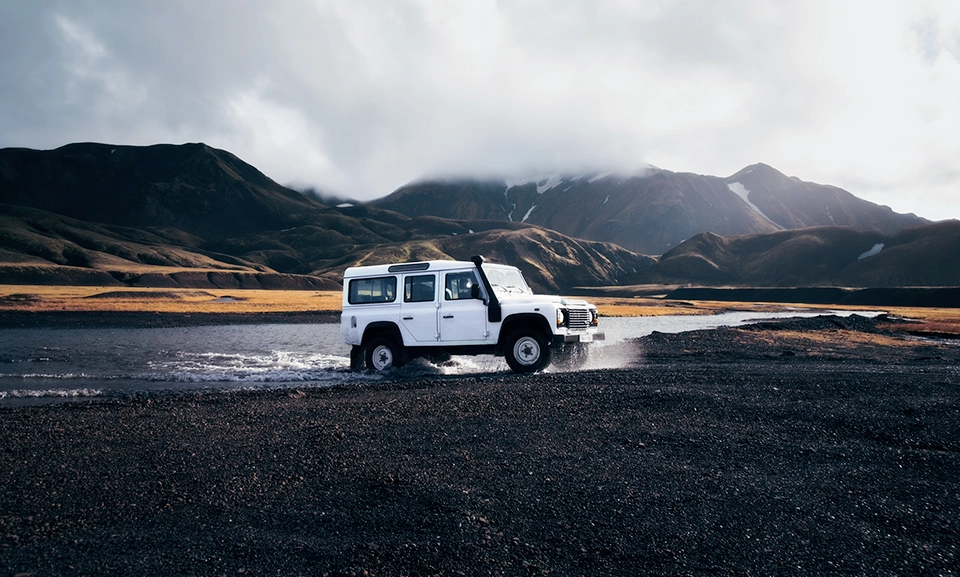 Photograph of a white car crossing a body of water.