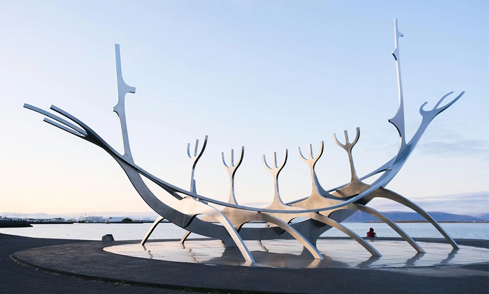 A large metal sculpture sitting in front of a body of water.